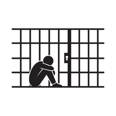 A solitary figure sits dejected behind the bars of a prison cell