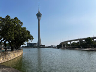 Scenic, sunlit view of the Macau Tower towering over the Sai Van Lake in Macau