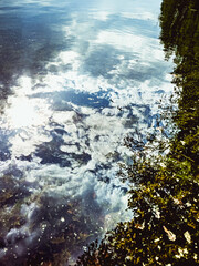 The calm waters reflect the cloudy sky and dark tree line overhead, creating a beautiful and serene landscape. High-quality photo.
