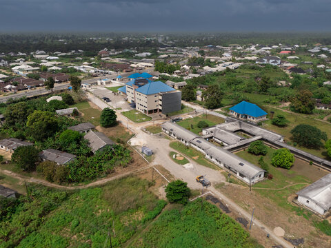 Aerial view of the community primary healthcare center with blue roofs nestled among lush greenery, with a mix of residential and institutional structures, Okobe, Rivers State, Nigeria.