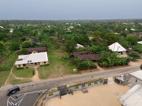 Aerial view of houses nestled among vibrant green trees and vegetation under a cloudy sky, Okobe, Rivers State, Nigeria.