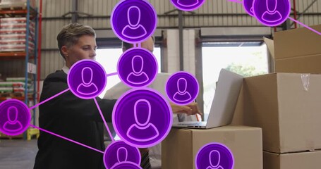 Animation of network of connections with icons over caucasian business people talking in warehouse - Powered by Adobe