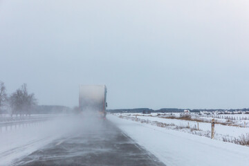 A truck overtakes on a snowy highway in bad weather conditions on a dangerous icy road.