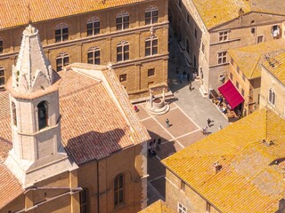 Aerial view of the well-preserved architecture and sun-kissed rooftops casting shadows on the town square, a timeless tableau, Pienza, Tuscany, Italy.