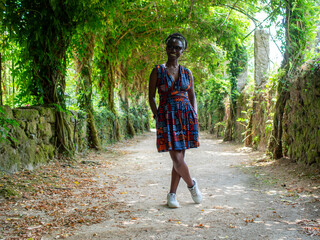 A beautiful woman is posing for a photo in a vegetation tunnel in a French garden.