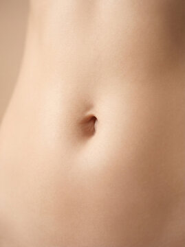 Close-up of a smooth, flawless human belly button with soft, neutral lighting