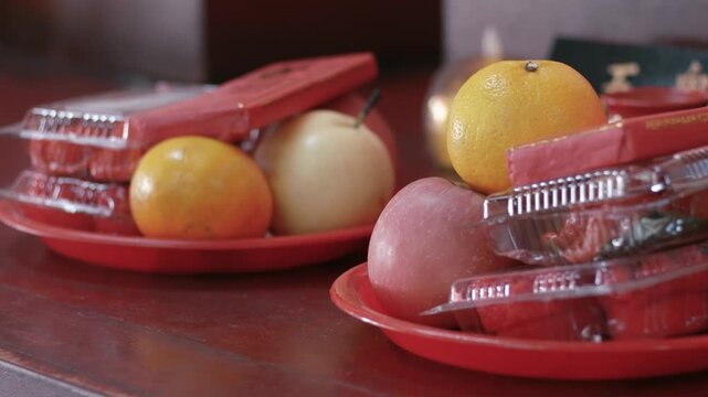 Selective focus of fruit and cake offering for god at chinese shrine. mandarin orange, apple, pear and cake for praying
