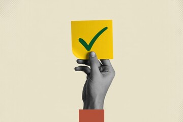 A hand holding a yellow sticky note with a green checkmark in front of a beige background