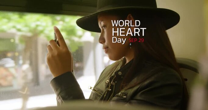 World heart day text banner against asian woman wearing a hat using smartphone in the bus