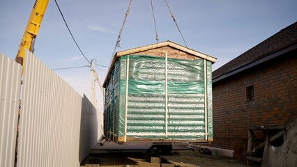 Lifting prefab house module with crane at construction site