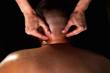 Masseur woman hands doing medical muscle neck massage of man in medical office in shadow. Rehab neck massage of human male patient back. Healthy rehabilitation massaging concept. Copy ad text space