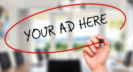 Hand writing 'Your Ad Here' on transparent screen in modern office