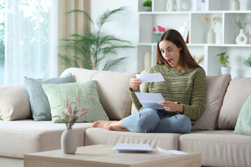 Amazed woman in green reading paper letter at home