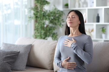 Asaian woman doing breathing exercises alone at home