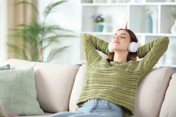 Relaxed woman in gren wearing headphone listening audio