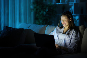 Happy woman in the night using personal computer at home