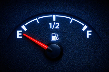  a fuel gauge on a textured black dashboard, with a red needle pointing to 1/2 full, and a white fuel icon.