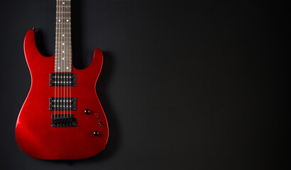 Red electric guitar against black background with copy space