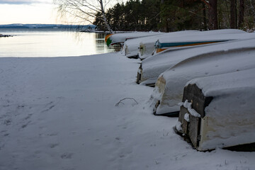 Boats and canoes covered in snow near lake Vattern Motala Sweden