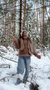 Teenage girl enjoying snow falling from a tree in a winter forest, reacting with pure joy. Authentic winter moment, playful lifestyle and emotional connection with nature.