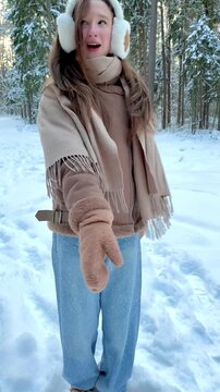 Teenage girl recording a vertical dance video in a snowy winter forest. Social media content creation, youth culture, self expression and dancing in nature.