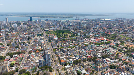 Aerial view of a bustling cityscape with towering buildings, vibrant green spaces, and a distant bridge stretching across the water, Maputo, Cidade de Maputo, Mozambique.
