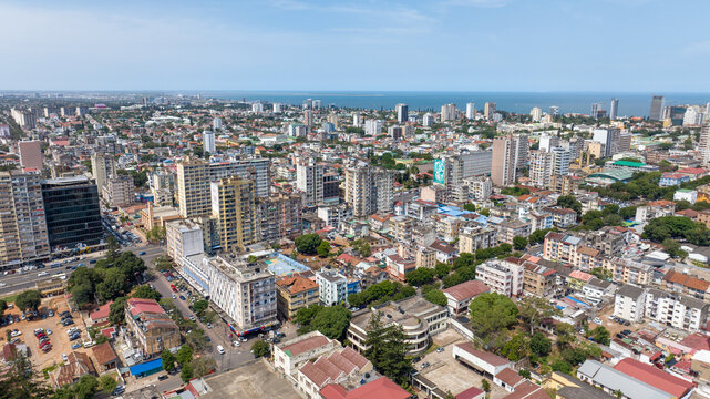Aerial view of a vibrant cityscape with a mix of modern high-rises and older buildings, contrasting against the deep blue ocean horizon, Maputo, Cidade de Maputo, Mozambique.