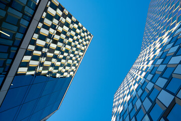 Modern urban architecture skyscraper facade in glass with blue sky reflection, dramatic perspective for corporate business headquarters branding
