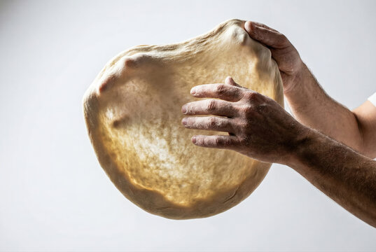 Manos estirando masa de pizza sobre fondo blanco