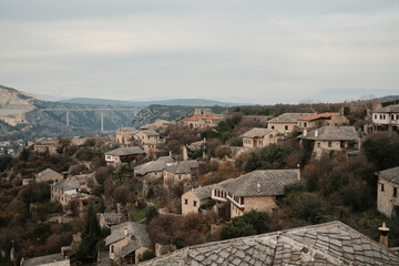 Obraz premium Traditional stone houses of Pocitelj village spread across a steep hillside with historic architecture and rugged terrain in Bosnia and Herzegovina.