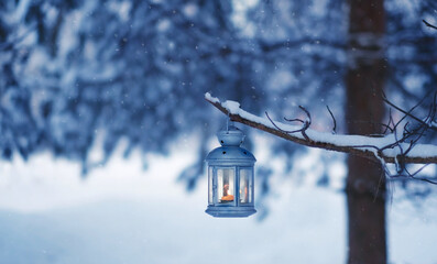 Christmas lantern hanging on tree branch, snowy forest nature background. fairy tale winter landscape with candle lantern. Christmas, Yule, New Year holidays vibes, festive winter season atmosphere