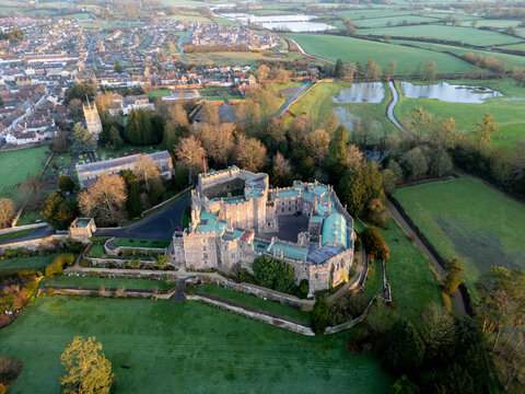 Aerial view of Berkeley Castle's ancient stone walls and verdant lawns meet the quaint town and flooded meadows under the soft glow of the morning light, Berkeley, England, United Kingdom.
