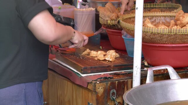 Indonesian street food vendor cutting Deep Fried Meatballs or 'Bakso Goreng' for customer. 'Bakso Goreng' is Popular Indonesia Street Food