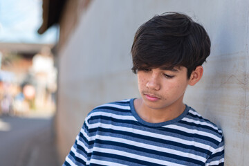 Obraz premium Depressed teenage boy in zebra t-shirt standing alone against grey wall, feeling lonely and pressured. Concept of family expectations, social anxiety, and mental health struggles.