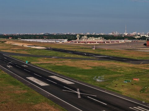 Aerial view of the runway stretches out, marked with stark white lines against the dark asphalt, toward the control tower, Berlin, Berlin, Germany.