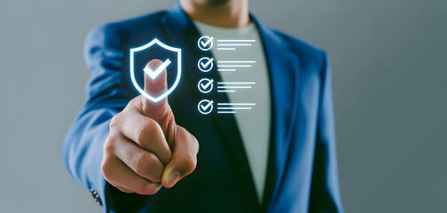 Businessman in blue suit jacket interacting with virtual security shield and checkmarks on gray background
