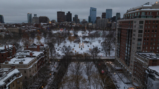 Aerial view of a snow-dusted Boston Common and Public Garden under a grey winter sky, framed by the city's architecture, Boston, Massachusetts, United States.