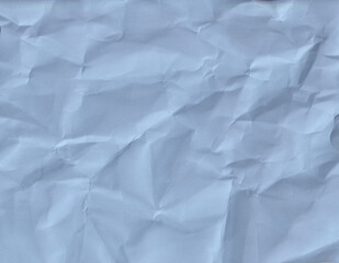 Fototapeta premium Crumpled blue paper texture on a flat surface in bright light during the day