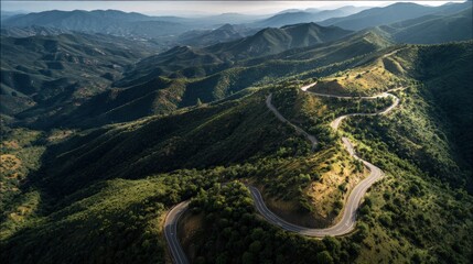 Birds-eye drone shot of a winding road through a mountainous region scenic landscape with dramatic shadows