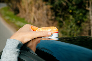 a man places a V16 warning beacon on his car roof