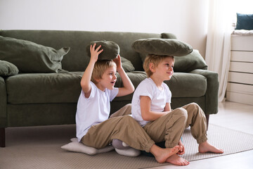kids boys have fun with pillows, sitting on the living room floor