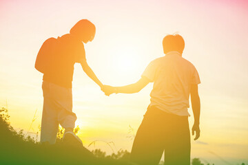 Mother encouraged her son outdoors at sunset, silhouette concept
