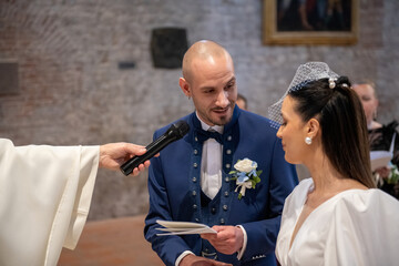 Happy young couple exchanging vows at the altar surrounded by family and friends in church