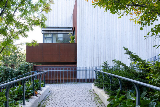 Modern urban residential courtyard with walkway and railing plus greenery showing architecture facade in strong perspective and clean outdoor light
