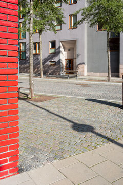 Red brick architecture at an urban street corner with cobblestone pavement texture and deep shadow creating strong minimalist surface detail