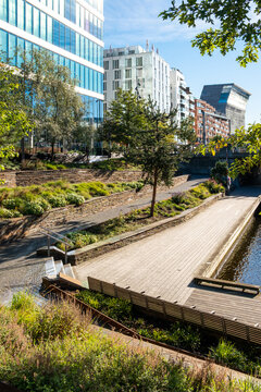 Modern urban park terraces with landscape walkway and wooden deck featuring architecture and greenery in warm sunlight for outdoor relaxation
