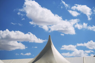 Chapiteau de tente blanche et ciel bleu nuageux.