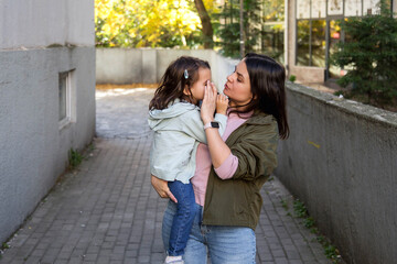 Fototapeta premium Mother checking little daughter eye outdoors, caring parent examining child health, concern and protection, family care concept, attentive motherhood, real people, authentic lifestyle