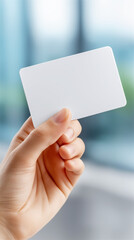 Hand holding blank white business card near window with soft daylight blur. Clean mockup for branding identity, contact details, marketing message and presentation, copy space.