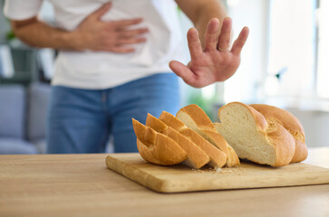 Gluten allergy, food intolerance of man refusing to eat white wheat bread slice on board. Person...